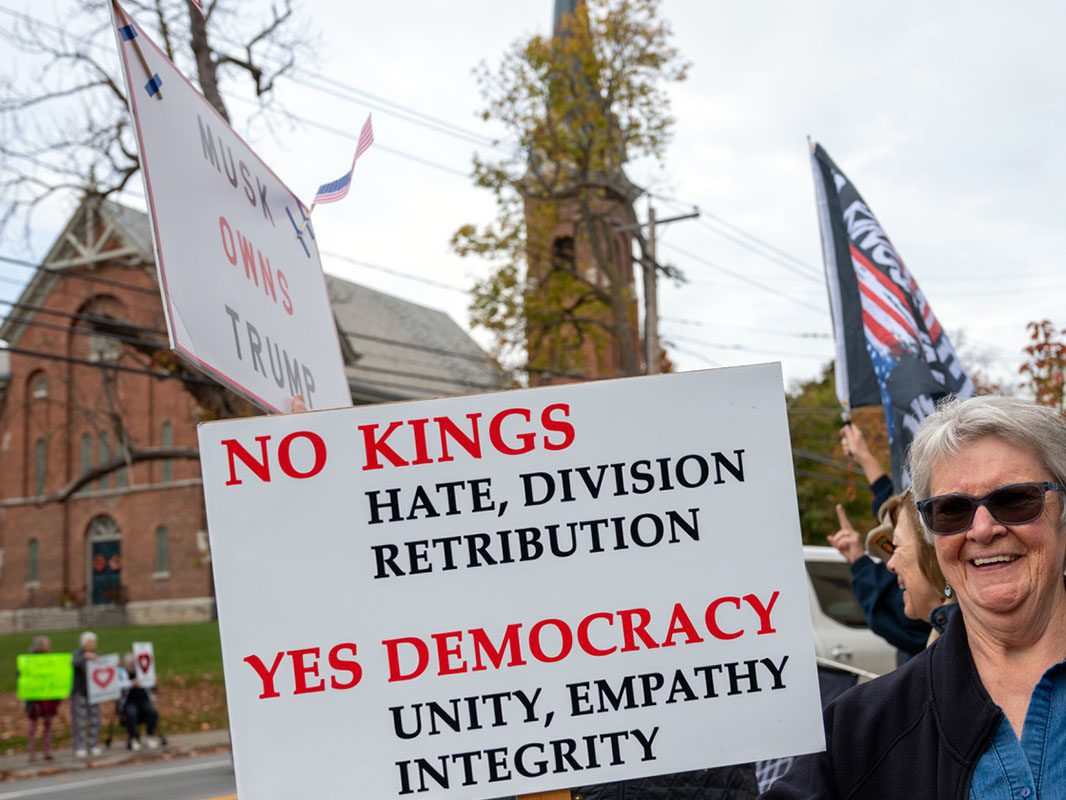 No Kings rally participants holding signs outdoors in Livingston County.